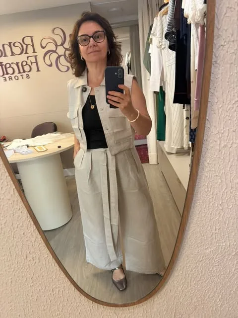 Look com colete e calça off-white sobre blusa preta